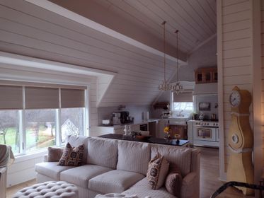 Living room with a sofa, a kitchen in the background, and a grandfather clock.