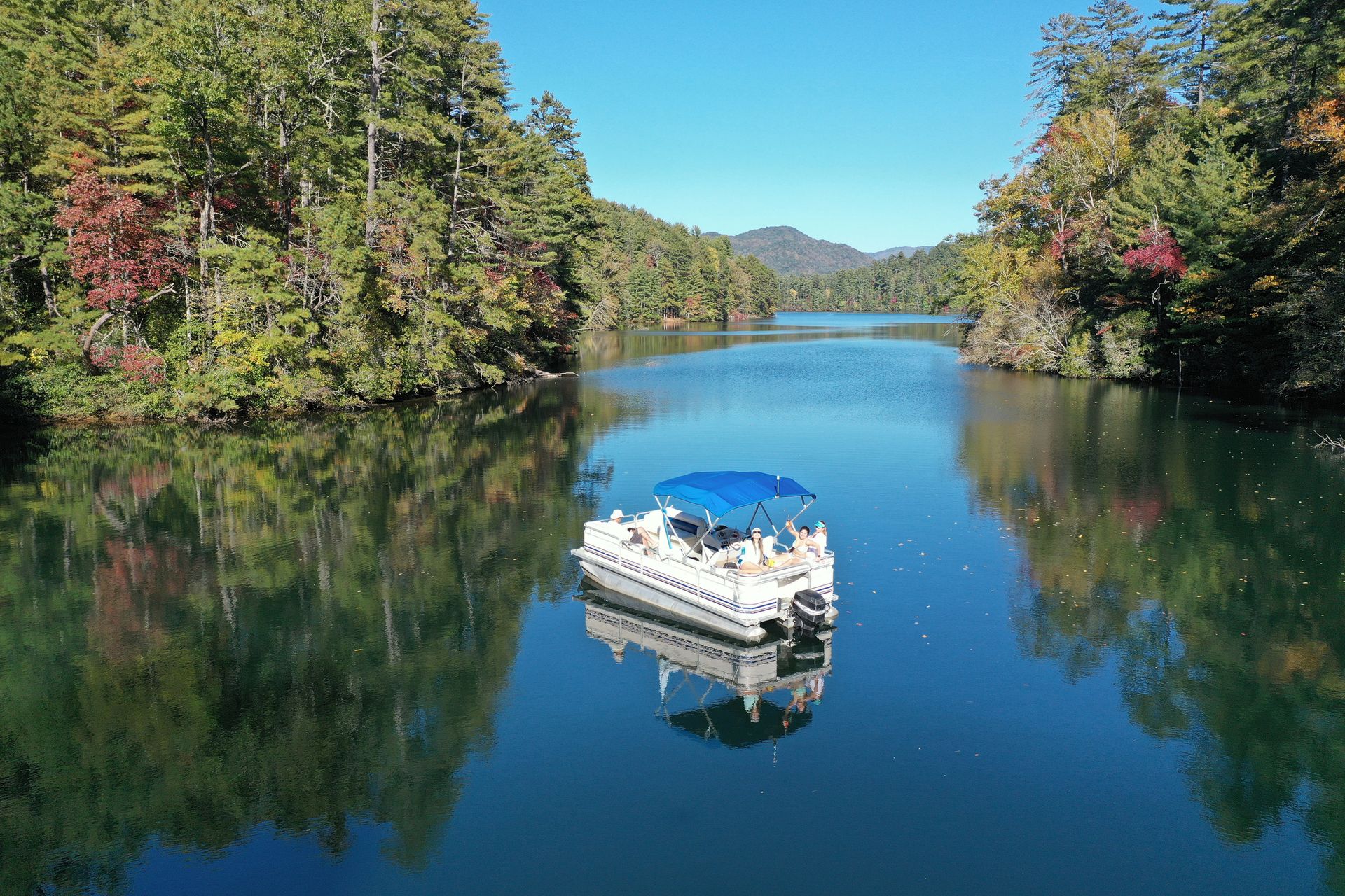 A pontoon boat is floating on a lake surrounded by trees.  | Cecelia Cook & Assoc. | Greenwood SC