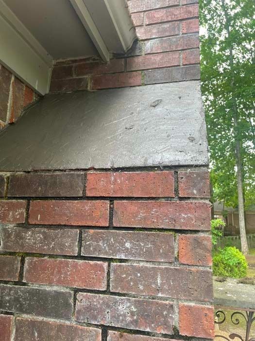 Brick column with gray concrete section under white overhang. Red-brown brick.