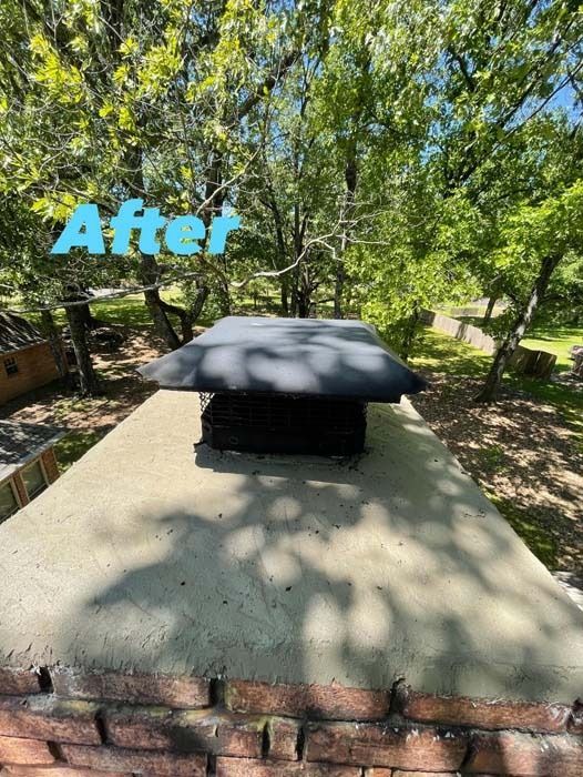 Chimney top with black cap, freshly painted. Green trees in background.