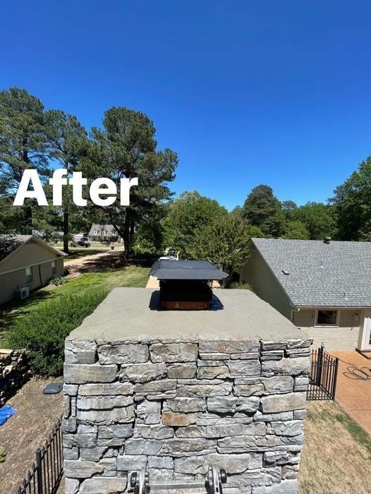 Stone chimney with a new black cap against a blue sky.
