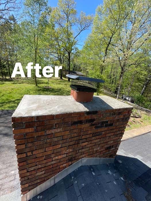 Brick chimney with a metal cap on a roof, surrounded by trees.