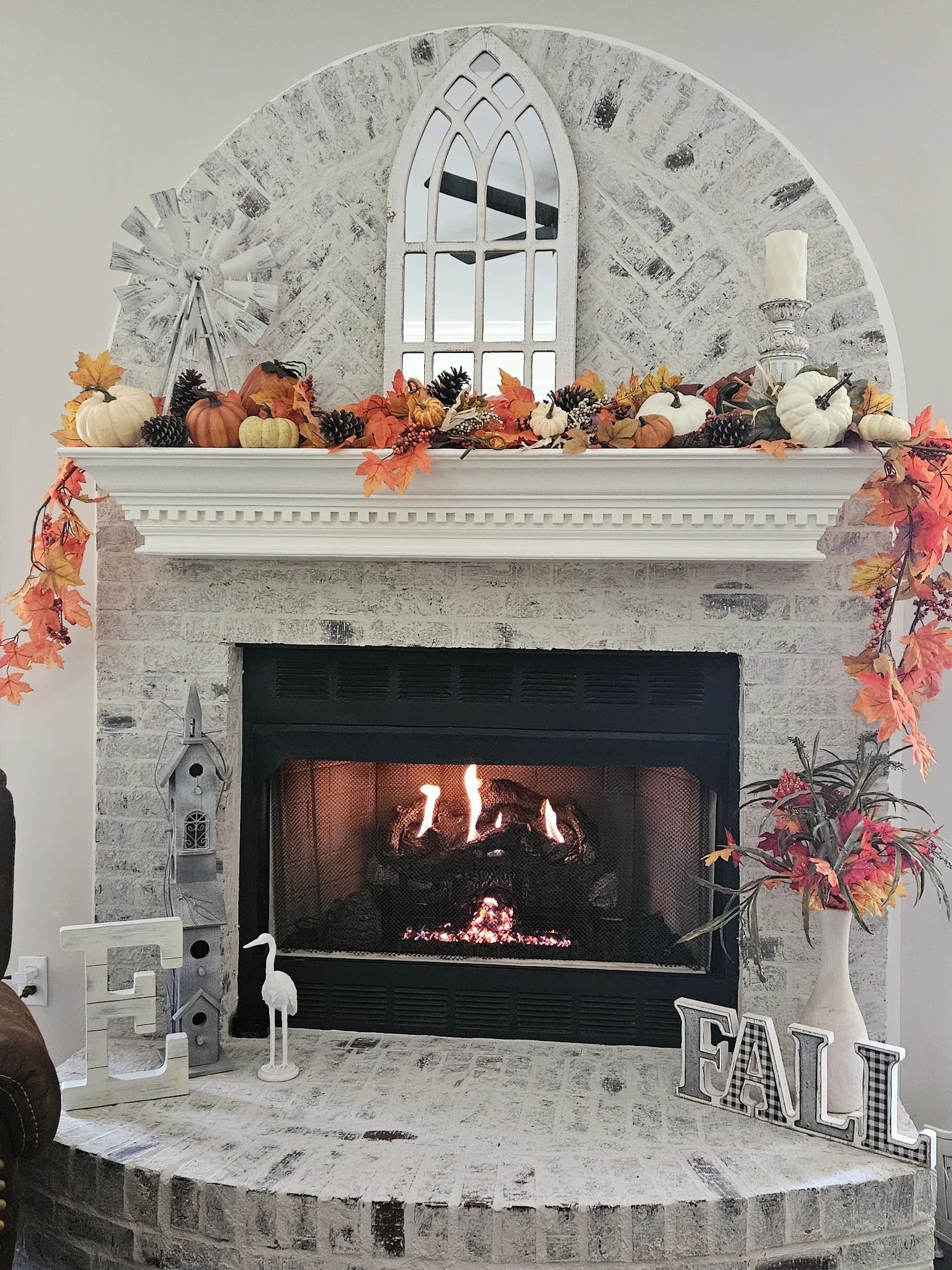 Fireplace decorated for fall with pumpkins and autumn leaves.