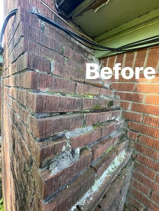 Damaged brick chimney corner with significant structural cracks and deterioration.