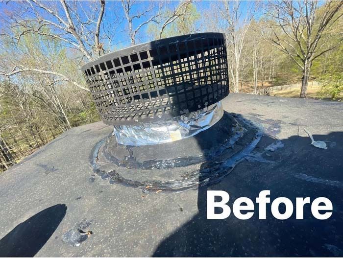 Black vent cap on a roof, before repair. Silver flashing, and surrounding black tar.