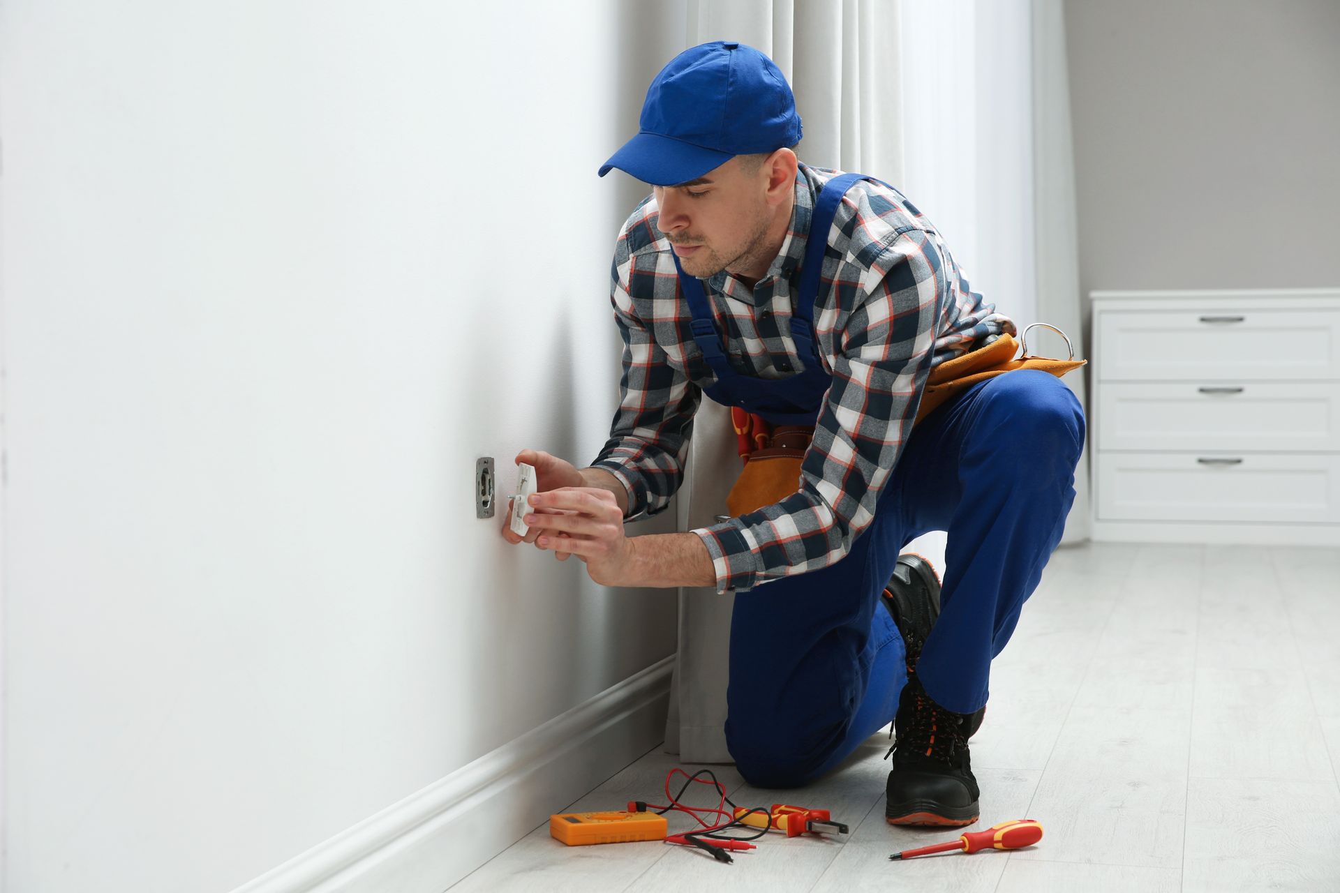 A professional male electrician repairing a power socket in a room