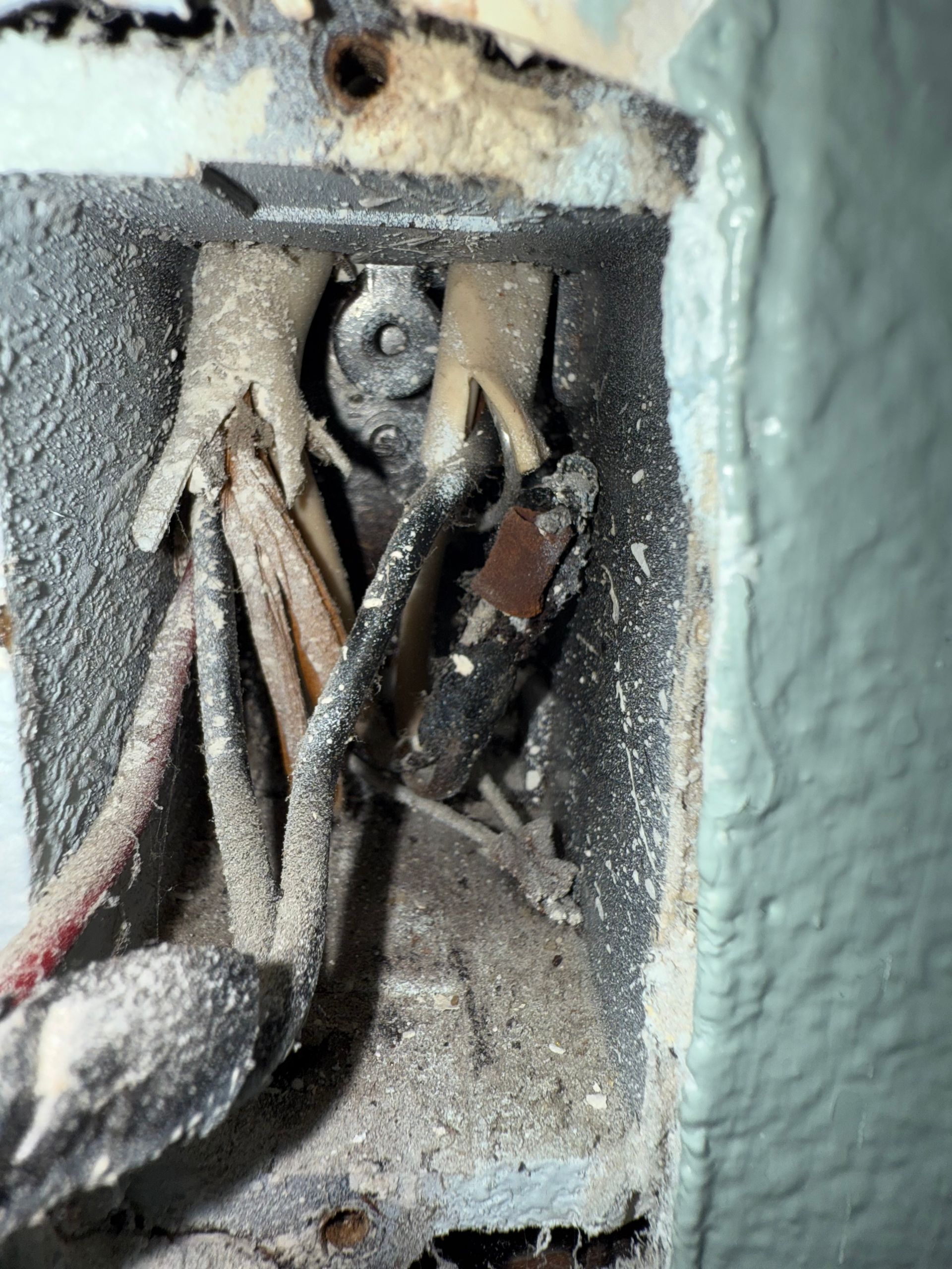 A close up of a dirty electrical box on a wall.