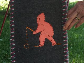 This is an image of a wall hanging with an Inuit person fishing.