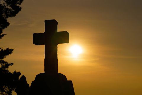 This is an image of a cross on a hill at sunset.