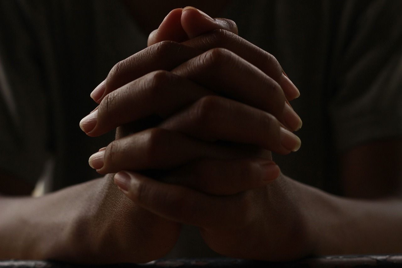 This is a photograph of hands folded in prayer.