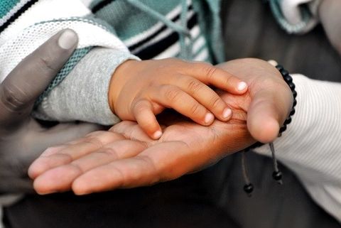 This is an image of small hand atop a larger hand signifying a father's blessing.