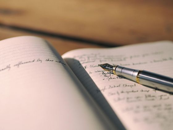 This is a photograph of a notebook with a fountain pen sitting on an open page.