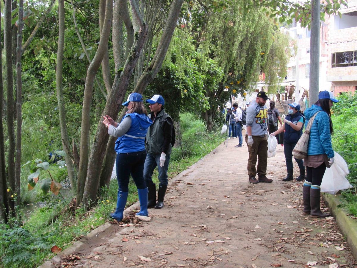 Un grupo de personas está de pie en una acera junto a los árboles.