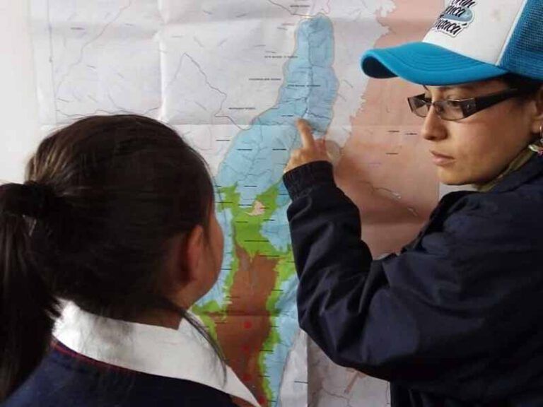 Un niño que lleva un sombrero azul y blanco señala un mapa.