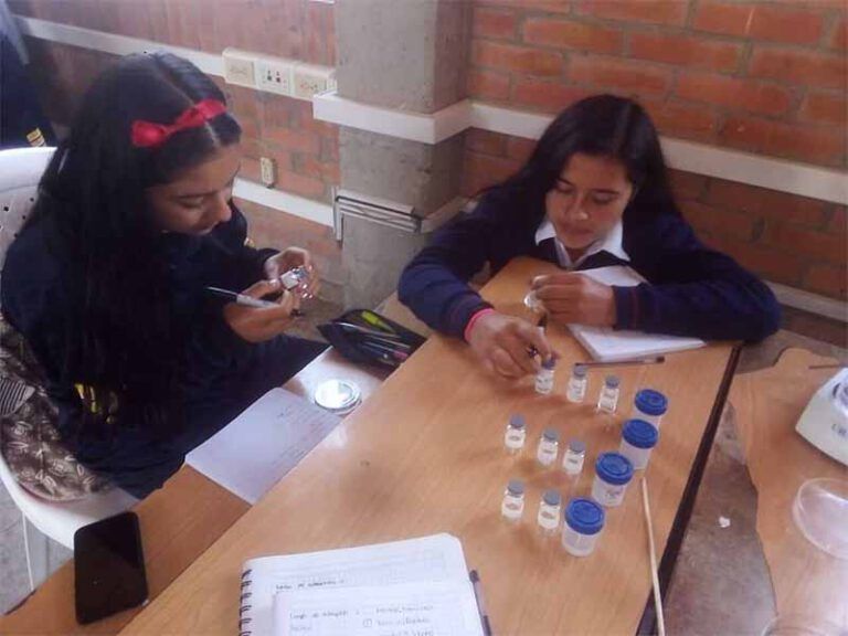 Dos chicas están sentadas en una mesa con botellas encima.
