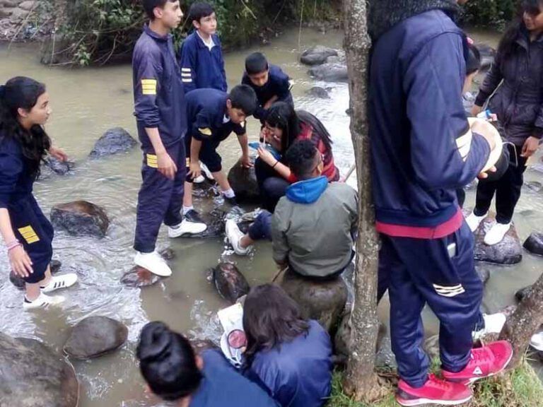Un grupo de personas está sentado en las rocas cerca de un arroyo.