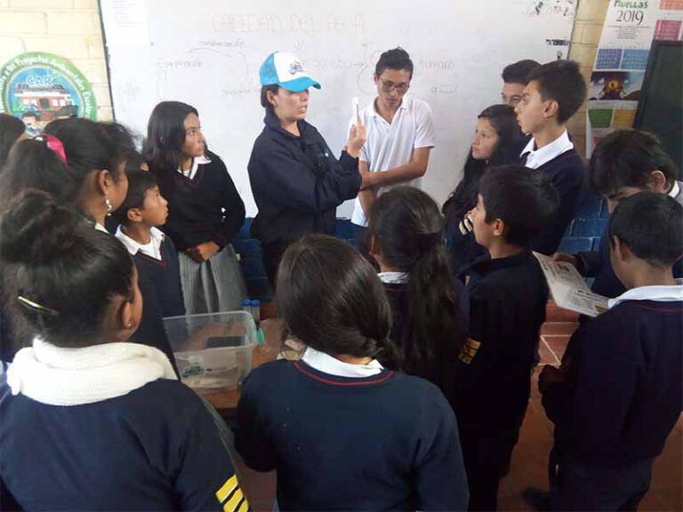 Un grupo de niños se reúnen en círculo en un aula.