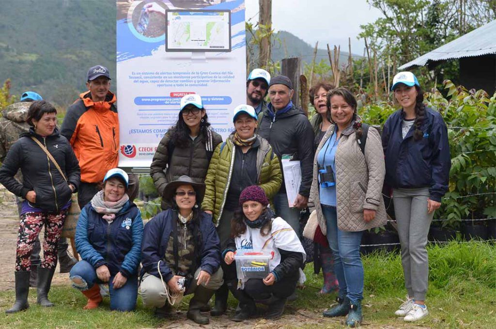 Un grupo de personas posan para una fotografía delante de un cartel.