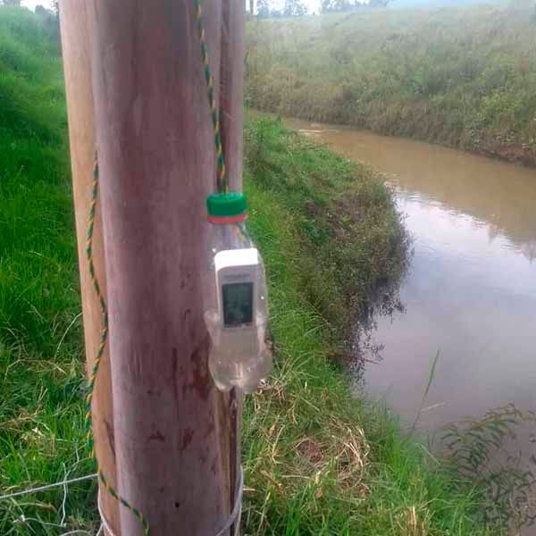 Un termómetro está fijado a un poste de madera al lado de un río.