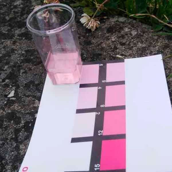 Un vaso de líquido rosa está encima de un trozo de papel.