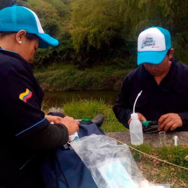 Dos hombres con sombreros azules están sentados uno al lado del otro cerca de un río.
