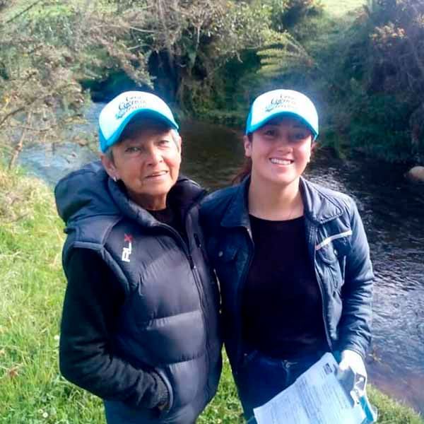 Dos mujeres paradas una al lado de la otra frente a un río.