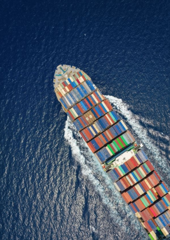 Cargo ship sailing on blue ocean, carrying colorful shipping containers.