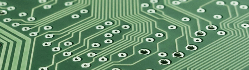 Green circuit board with intricate pathways and electronic components.