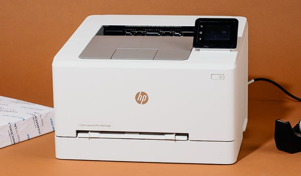 a white hp printer is sitting on a table next to a ream of paper.