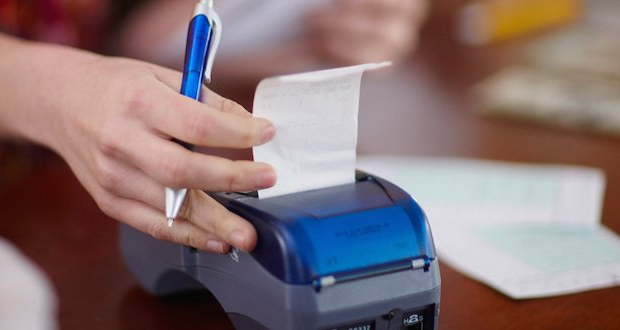 a person is pulling a receipt from a printer .