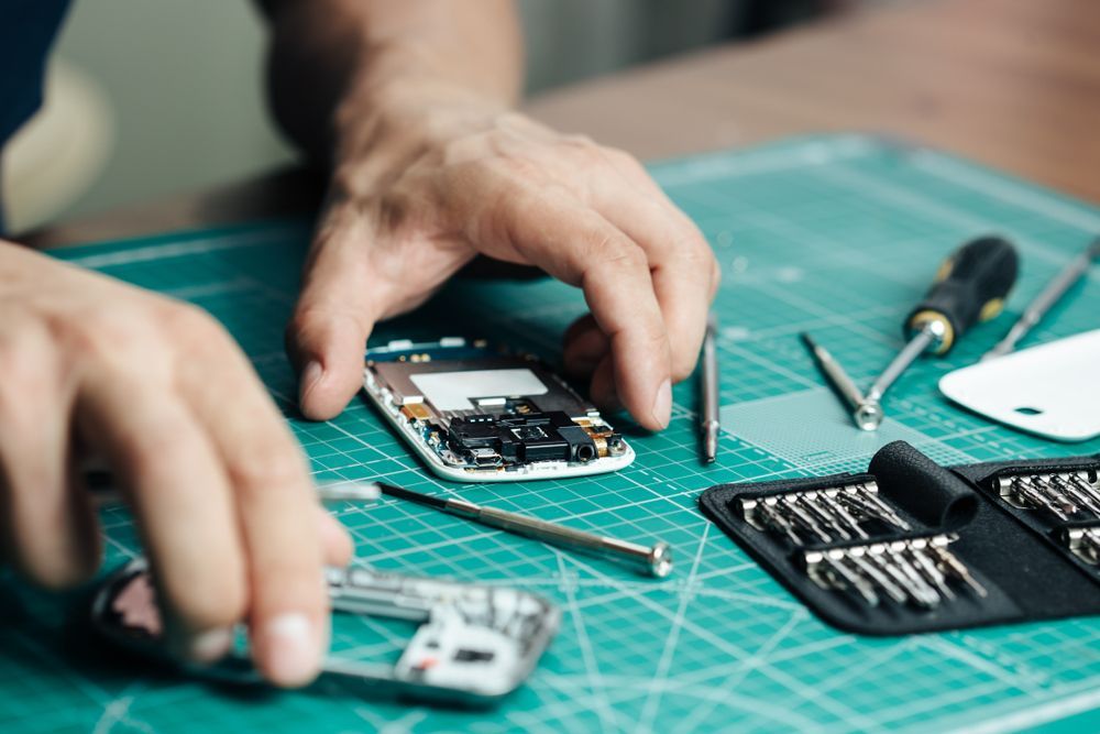 A man is repairing a barcode scanner on a cutting mat.