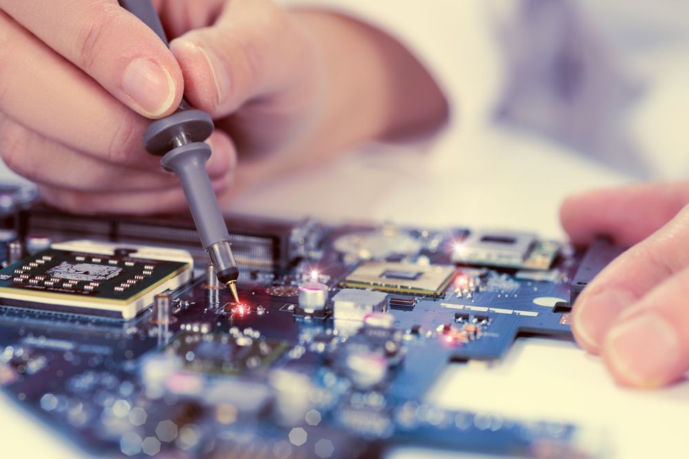 A person is working on a motherboard with a soldering iron.