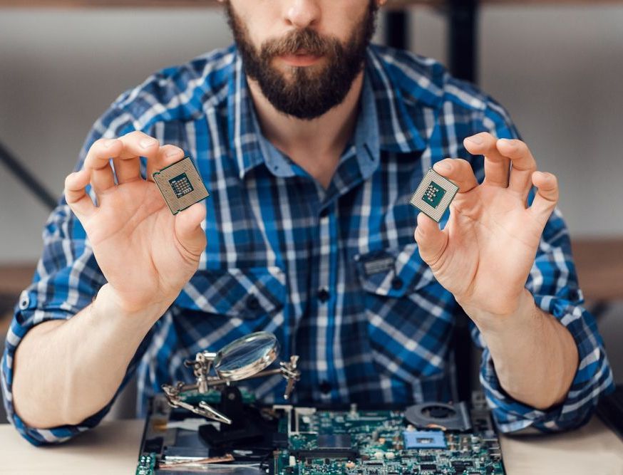 a man in a plaid shirt is holding two cpu chips in his hands, providing third party maintenance services