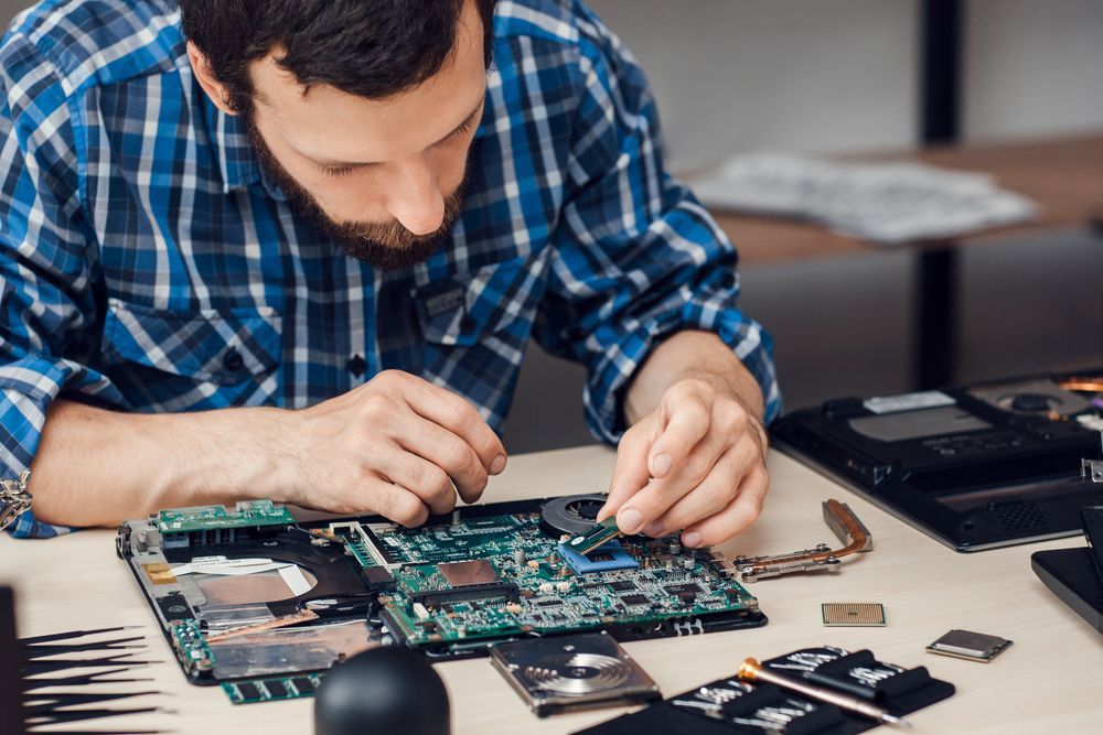 a man in a blue, plaid flannel is providing third party maintenance to hardware 