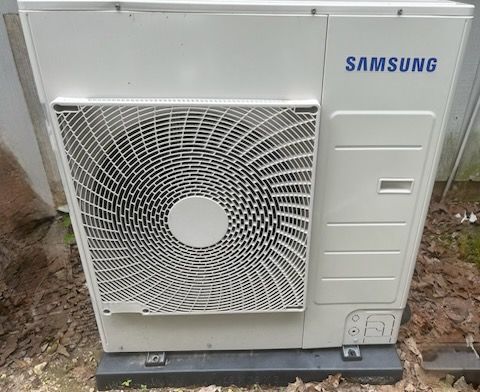 A person servicing an opened white indoor wall-mounted air conditioning unit.