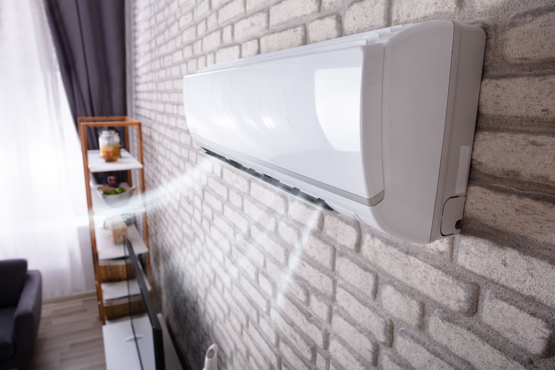 A white wall-mounted air conditioner blowing cool air.