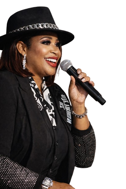 Woman in black hat and blazer holding a microphone, smiling, with a silver watch.