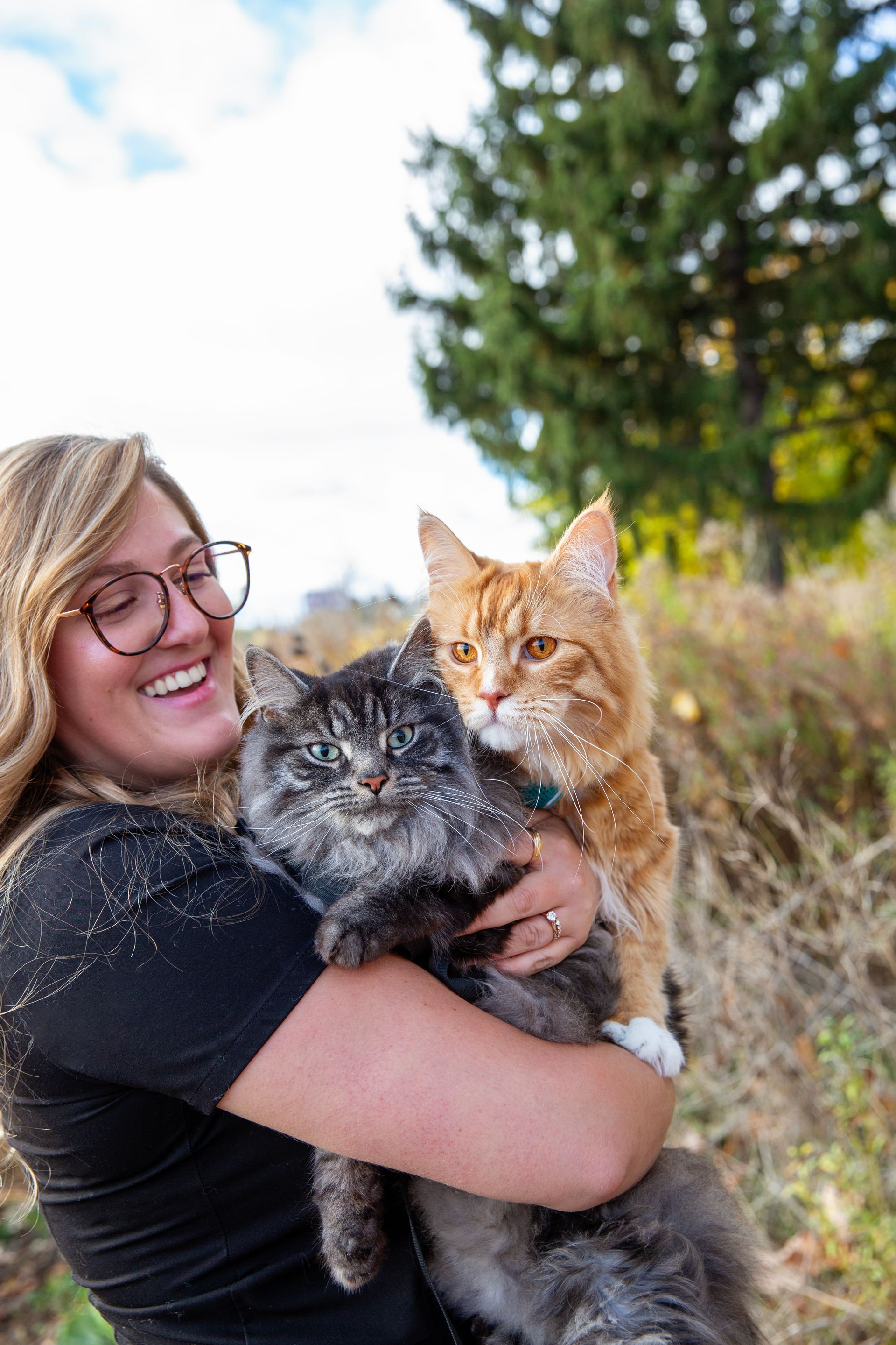 Veterinarian in navy scrubs holding an orange tabby cat, smiling in a clinic setting.