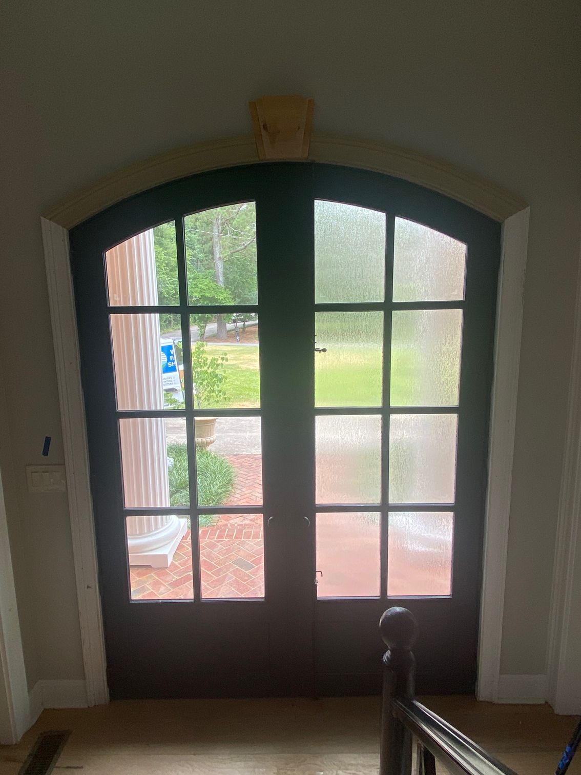 A door with a view of a yard and a staircase behind it.