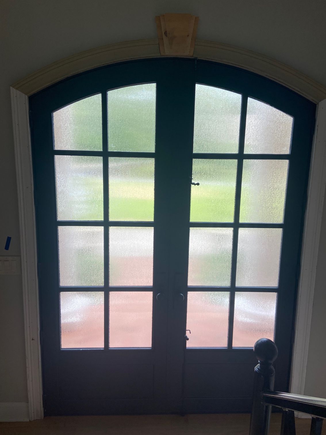 A pair of black doors with arched windows in a room.