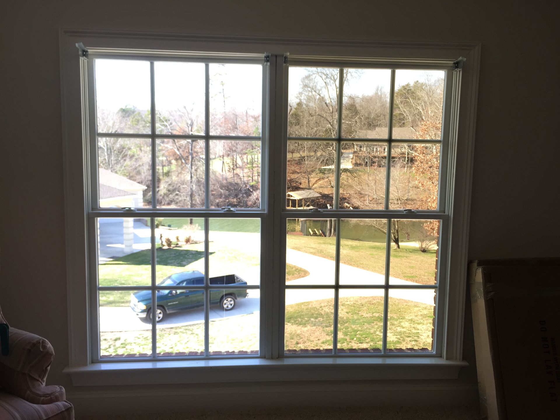 A car is parked in a driveway in front of a window.