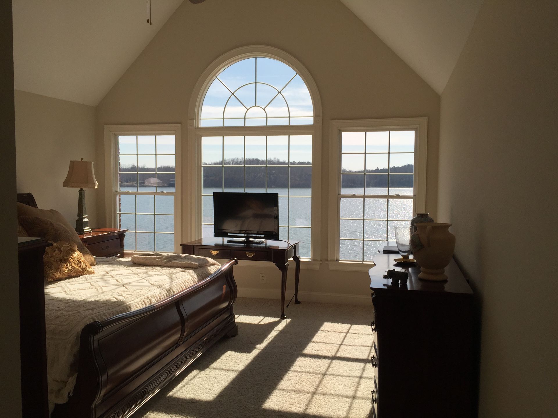 A bedroom with a large window overlooking a lake