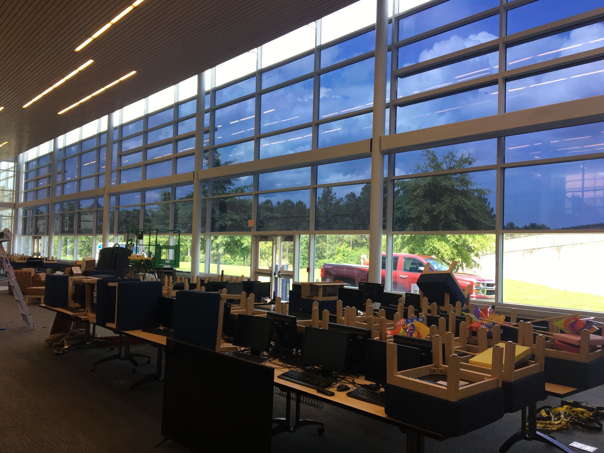 A room with a lot of windows and tables with computers on them.