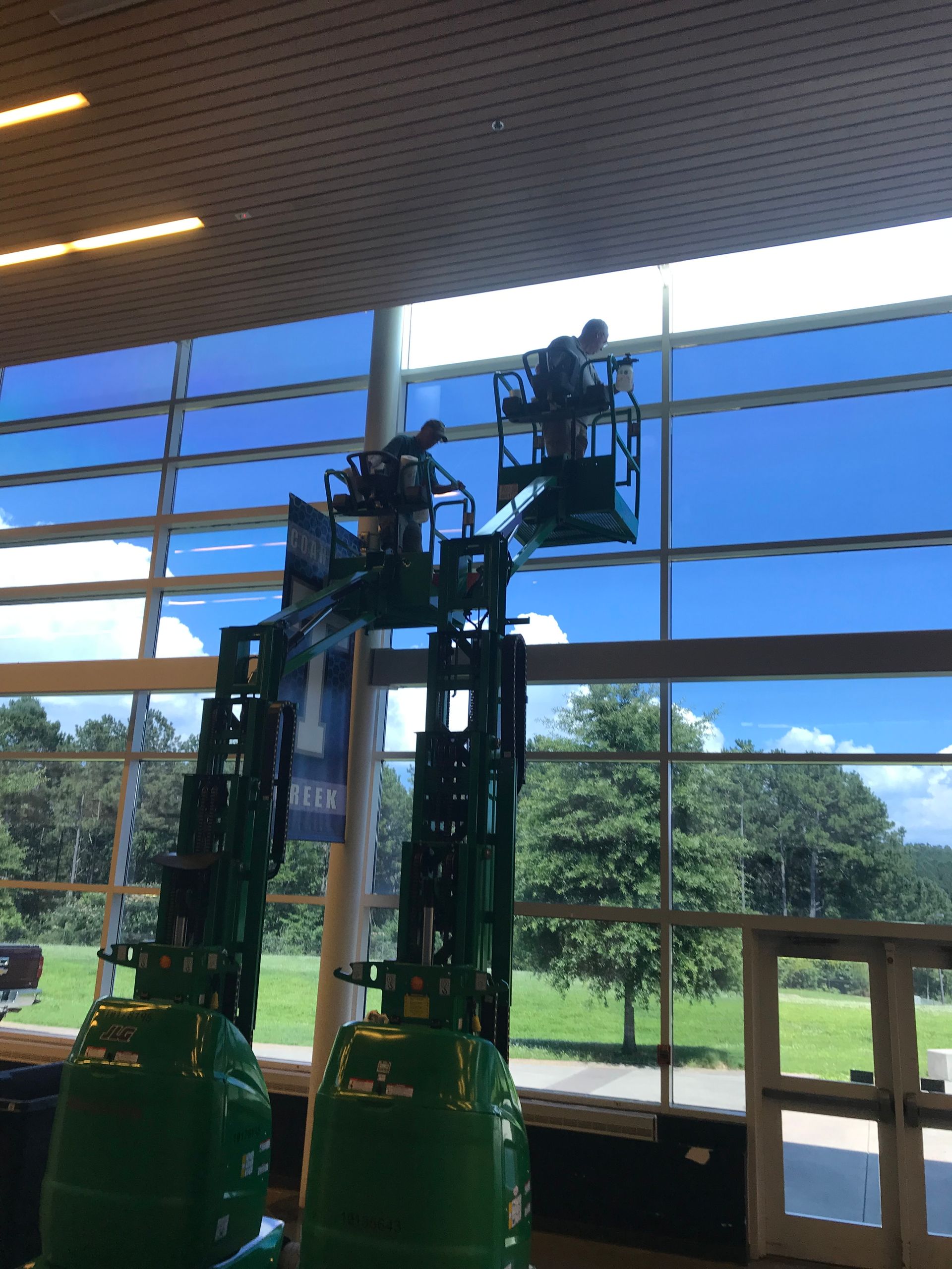 A man is cleaning a large window with a lift.