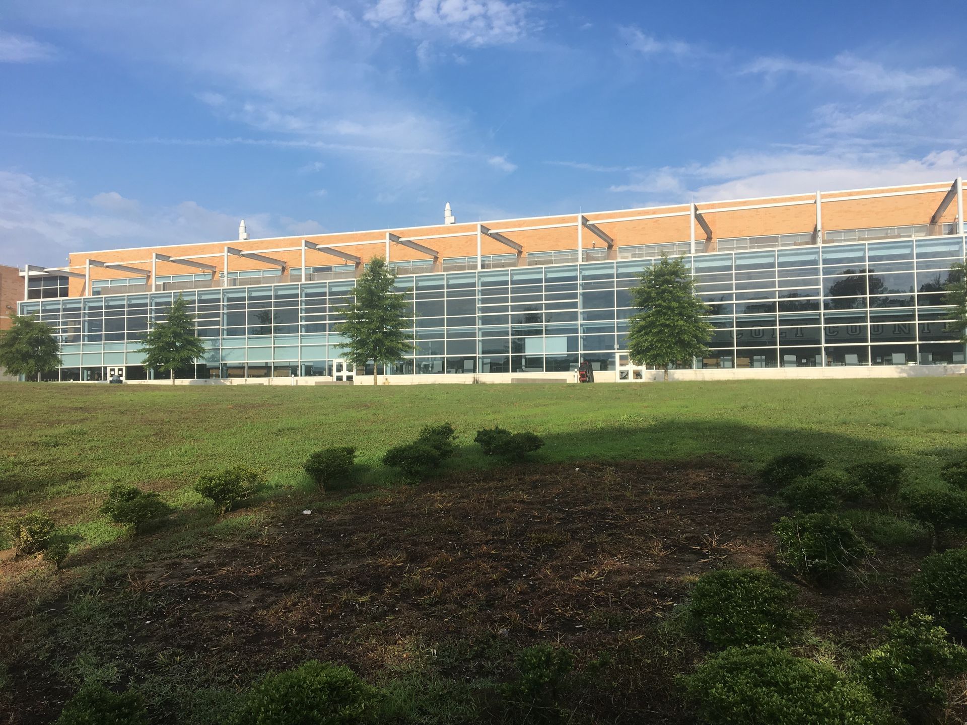 A large building with a lot of windows is surrounded by trees and grass.