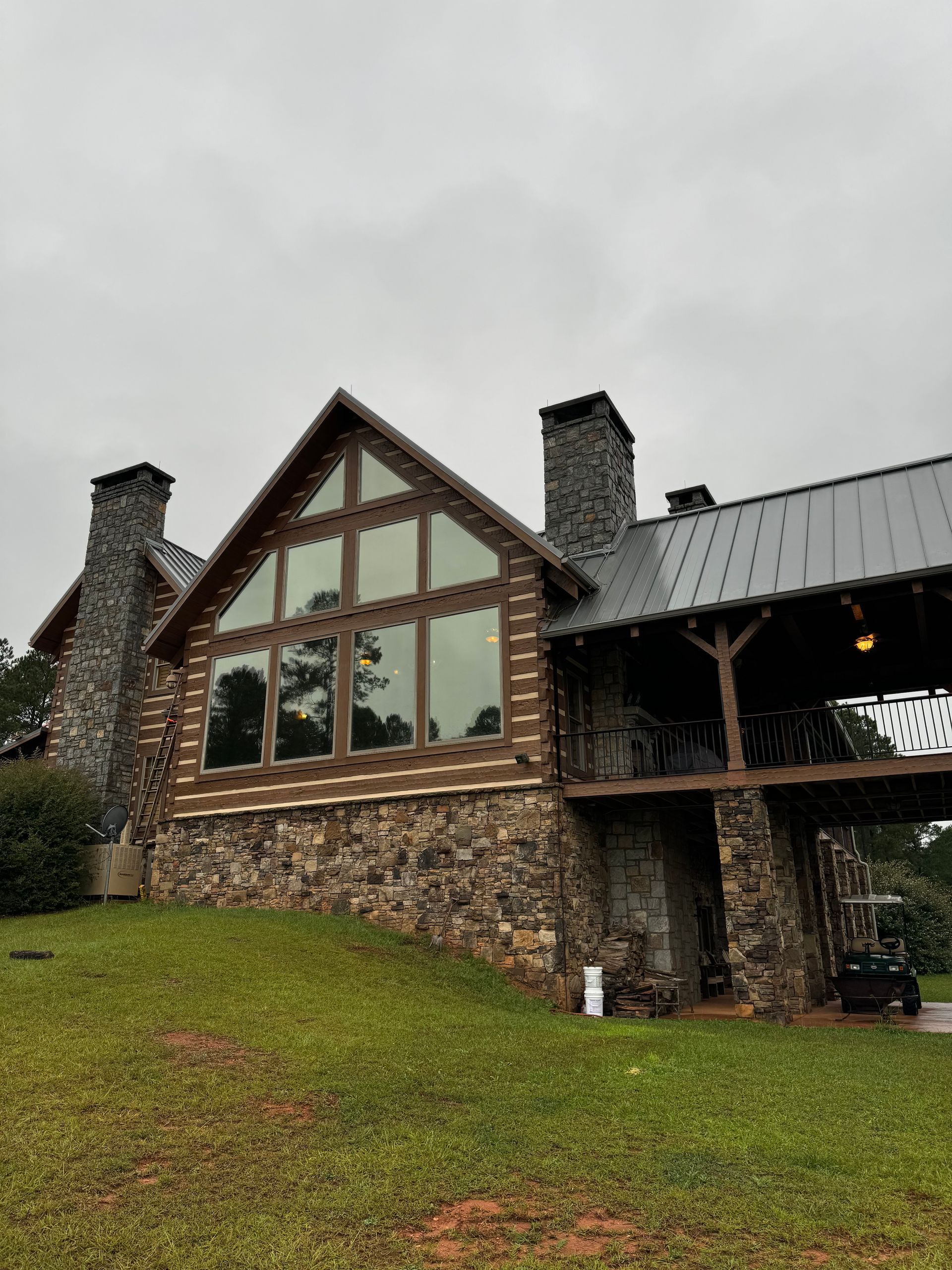 A large log cabin is sitting on top of a grassy hill.