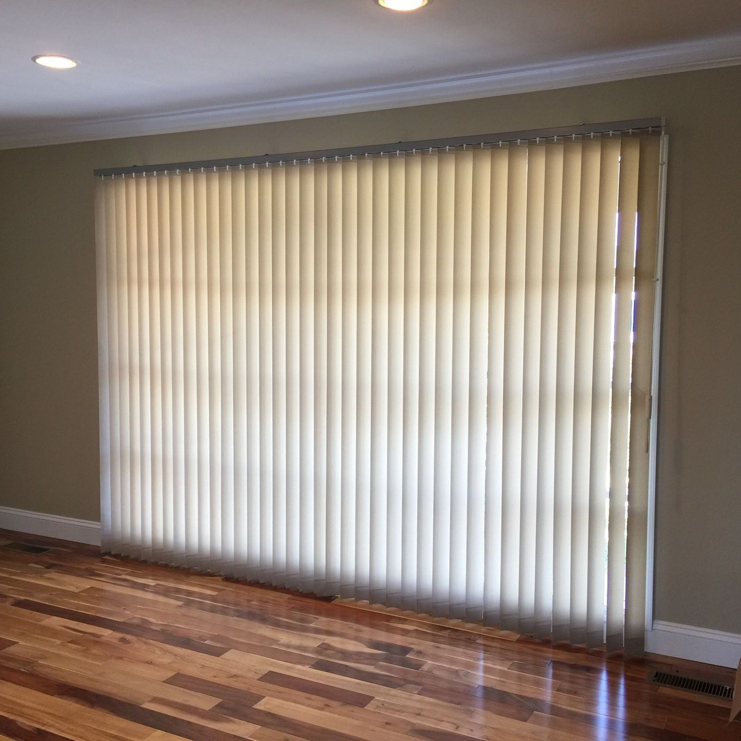 A living room with a large window and vertical blinds on it.
