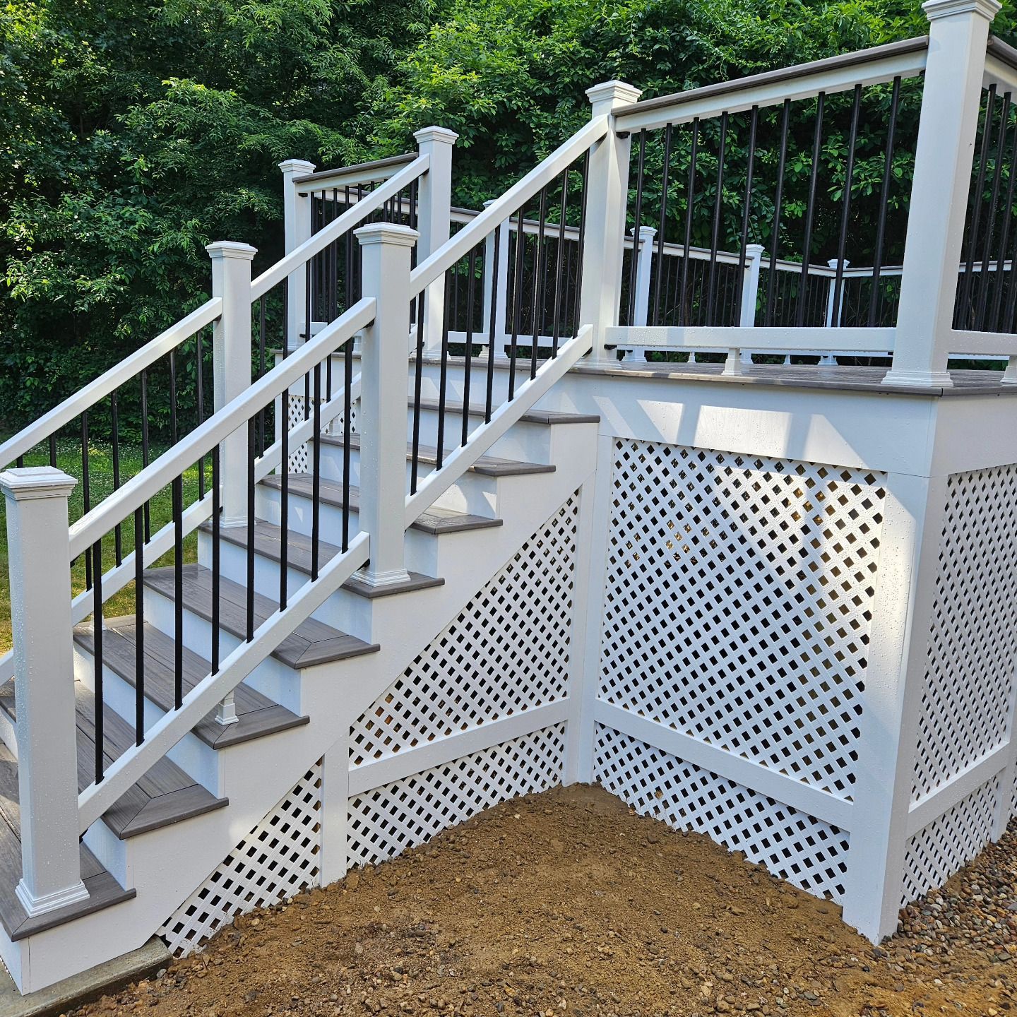 A white deck with stairs and a black railing