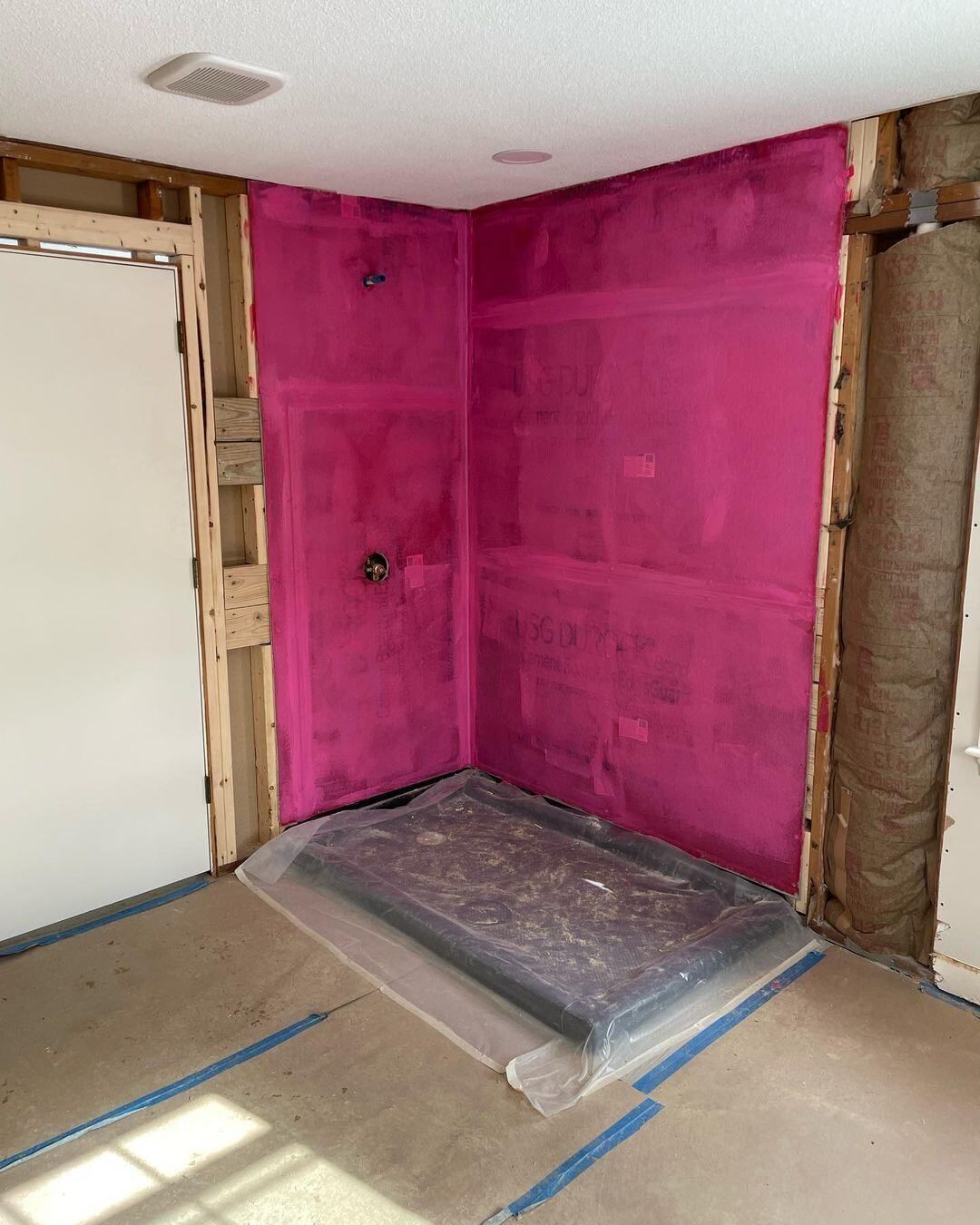 A room with a pink wall and a white door.