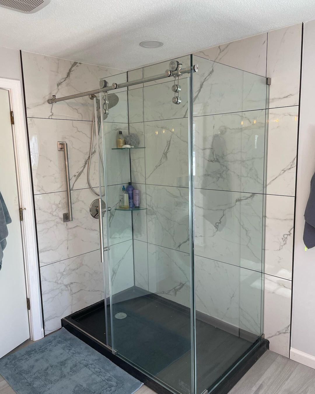 A bathroom with a walk in shower with sliding glass doors